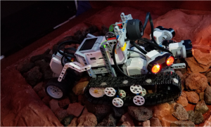 A LEGO robot drives along a simulated lunar surface.